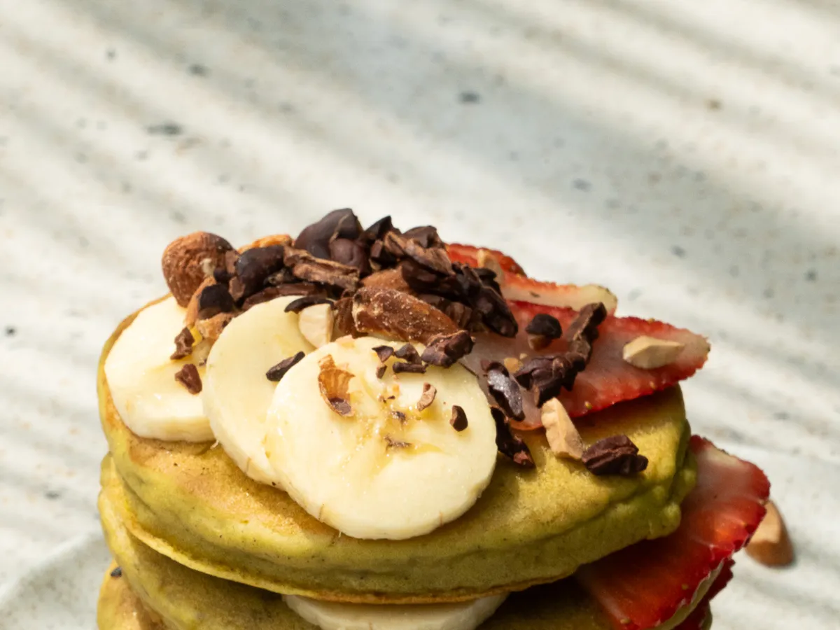 Tall stack of green pancakes with banana and cacao nibs at Smash Avocaderia, Soul Lifestyle Apartments